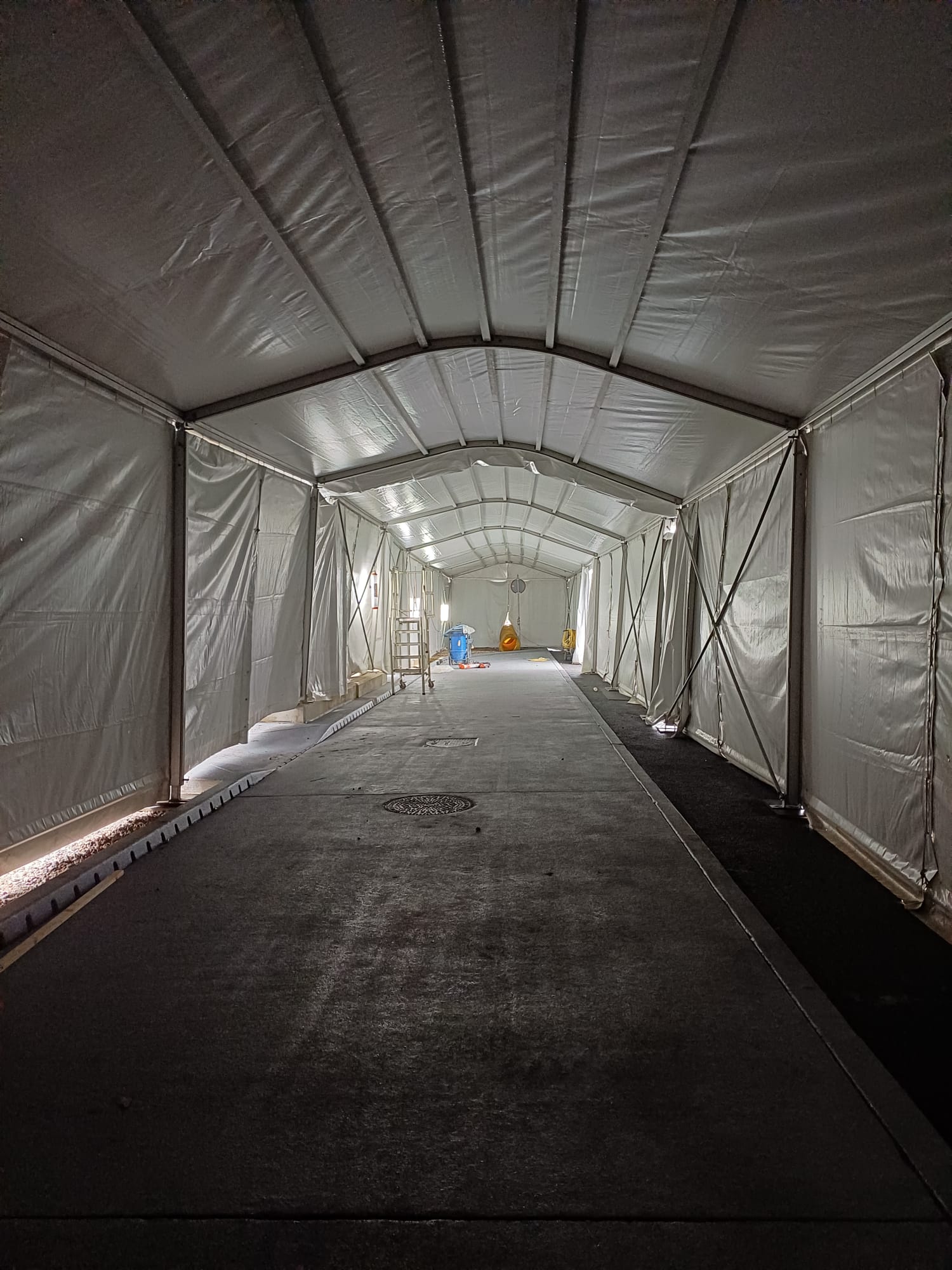 Lange doorwerktent over een vloer die gecoat wordt, met verlichting langs de zijwanden