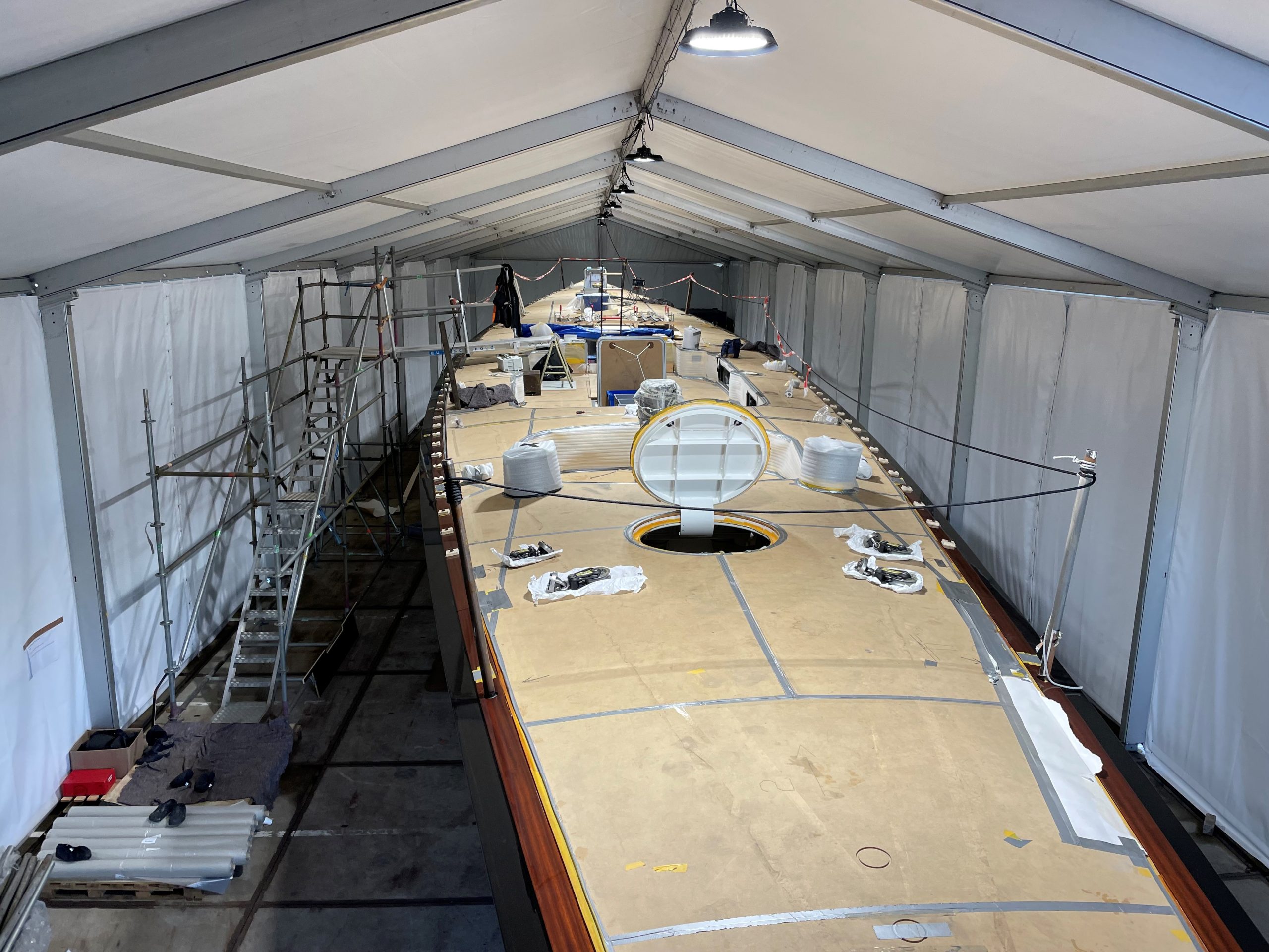 Werktent van 10 bij 40 meter voor onderhoud aan een jacht, met steigers en verlichting